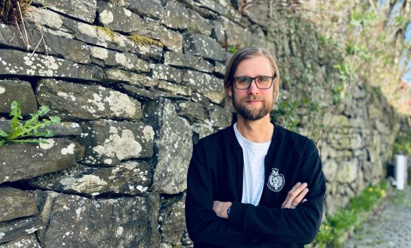 Portrett av mann som står foran en steinmur