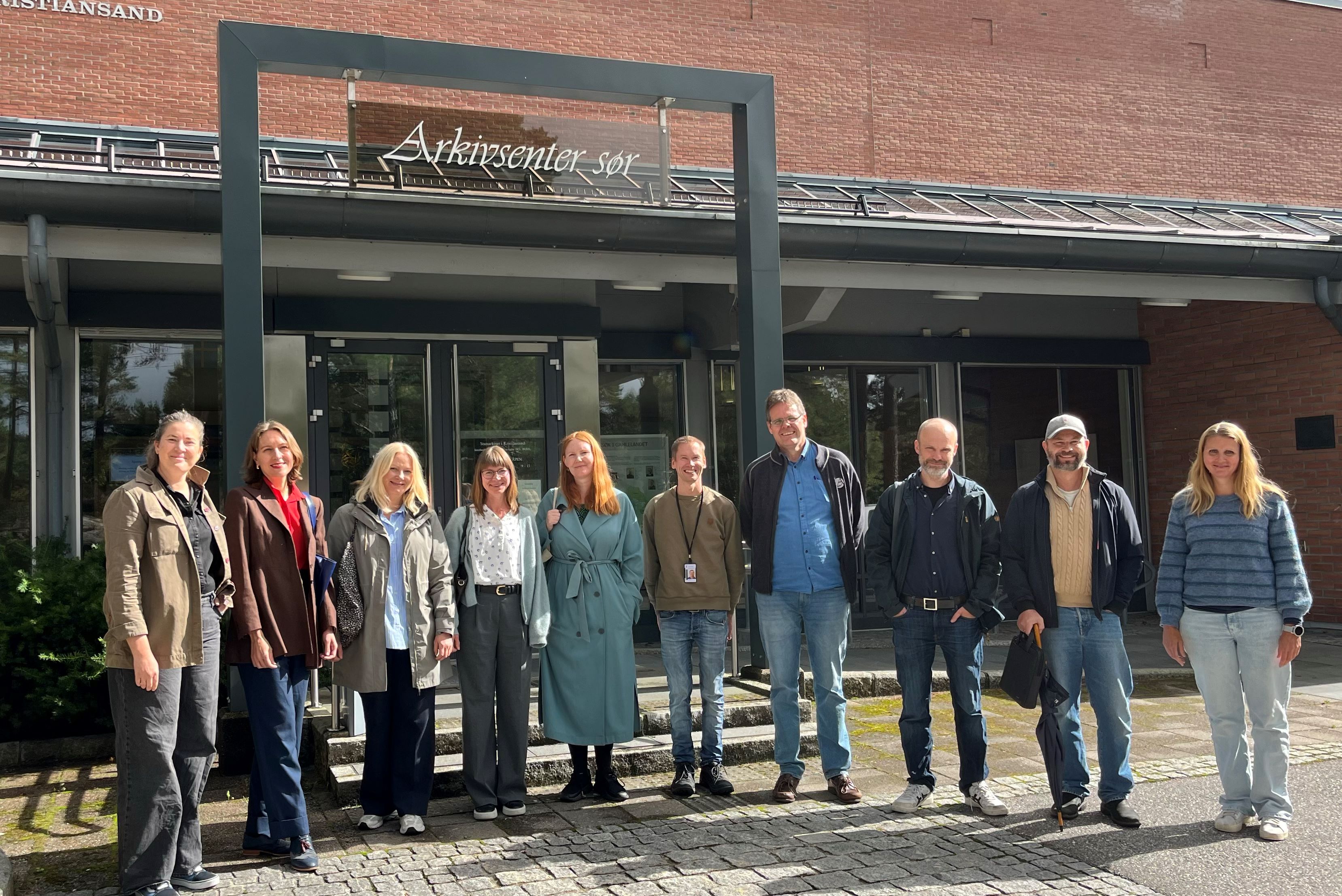 Bilde av ti personer utenfor en bygning med påskriften Arkivsenter sør