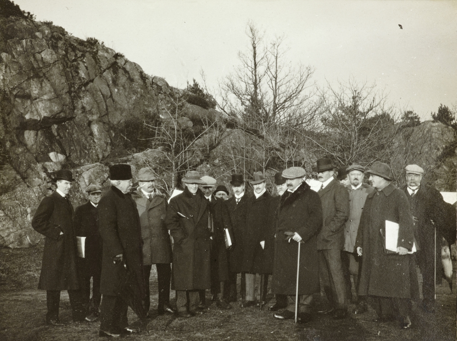 Sort hvitt fotografi av en rekke personer med hatt og frakk
