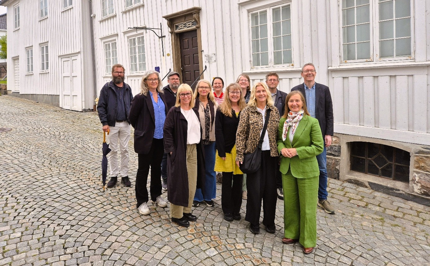 Gruppebilde utenfor hvitmalt hus